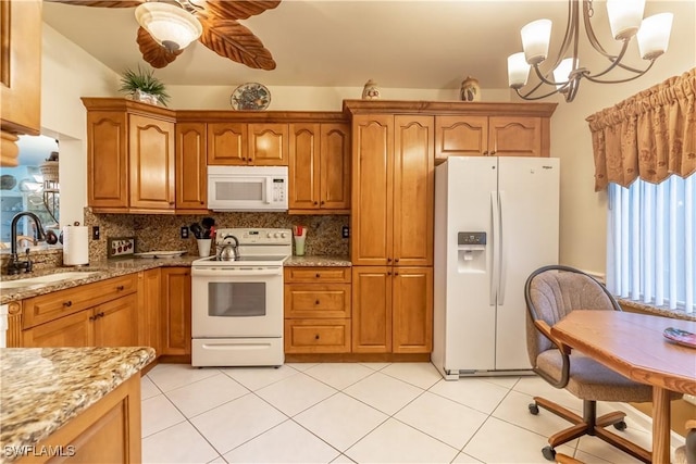 kitchen with tasteful backsplash, light stone counters, brown cabinetry, white appliances, and a sink