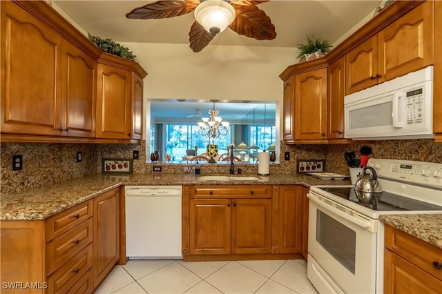 kitchen with a sink, white appliances, brown cabinetry, and ceiling fan with notable chandelier