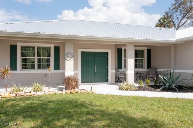 doorway to property featuring a porch and a lawn