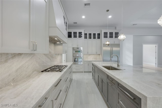 kitchen featuring stainless steel appliances, white cabinets, a sink, glass insert cabinets, and pendant lighting