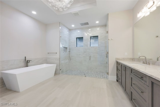 full bath with a shower stall, a freestanding bath, a notable chandelier, vanity, and recessed lighting