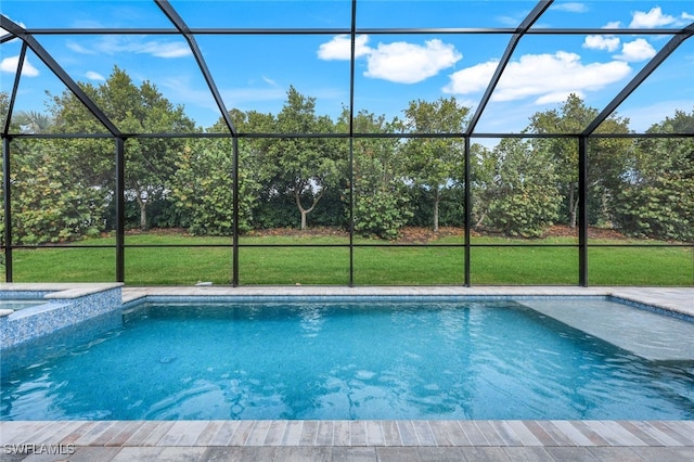 view of pool with a lanai, a pool with connected hot tub, and a lawn