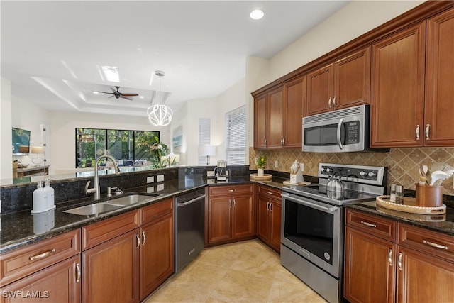 kitchen featuring stainless steel appliances, sink, decorative backsplash, and dark stone countertops