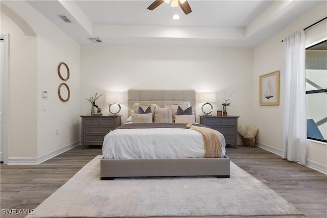 bedroom featuring wood-type flooring, a raised ceiling, and ceiling fan