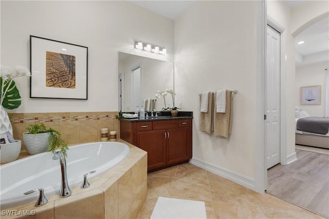 bathroom featuring tile patterned flooring, vanity, and a relaxing tiled tub