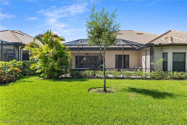 rear view of house with a yard, a lanai, and ceiling fan