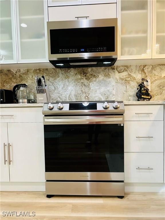 kitchen featuring backsplash, appliances with stainless steel finishes, and white cabinets