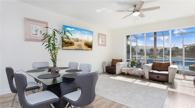 dining area with ceiling fan, baseboards, a sunroom, and light wood-style floors