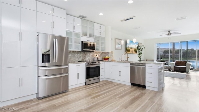 kitchen with visible vents, white cabinets, stainless steel appliances, pendant lighting, and a sink