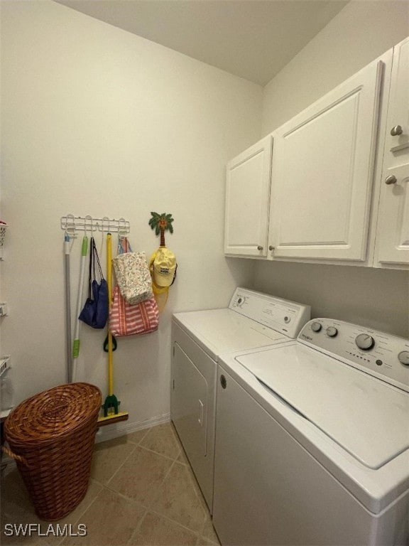 clothes washing area with tile patterned floors, washing machine and dryer, and cabinets