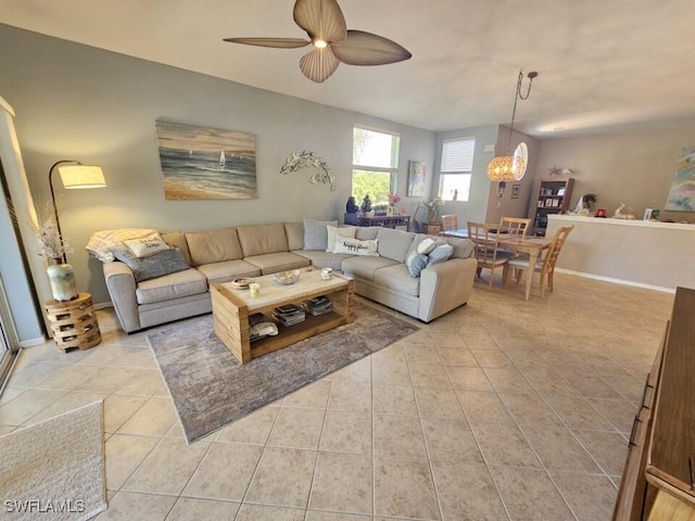 tiled living room with ceiling fan with notable chandelier