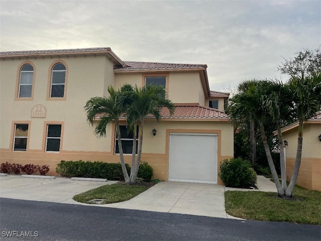 mediterranean / spanish home with a tiled roof, concrete driveway, and stucco siding