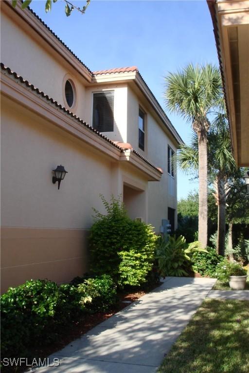 view of side of home featuring a tile roof, an attached garage, and stucco siding