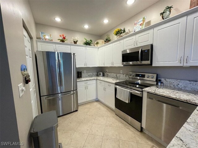 15495 Bellamar Cir Unit 2222, Fort Myers, FL 33908 - kitchen featuring appliances with stainless steel finishes, light tile patterned flooring, recessed lighting, white cabinetry, and light stone countertops