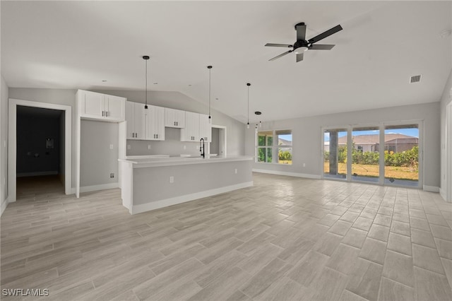 unfurnished living room with a ceiling fan, vaulted ceiling, a sink, light wood-type flooring, and baseboards