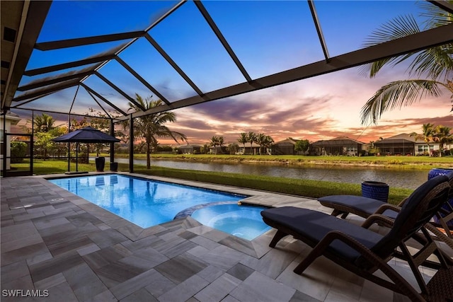 pool at dusk with a water view, an in ground hot tub, glass enclosure, and a patio