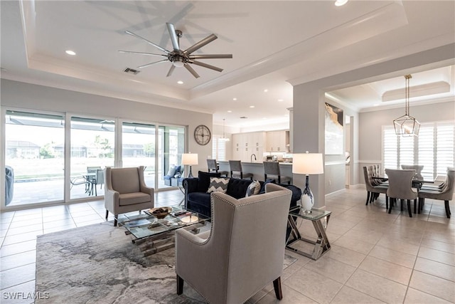 tiled living room featuring crown molding, plenty of natural light, a raised ceiling, and ceiling fan