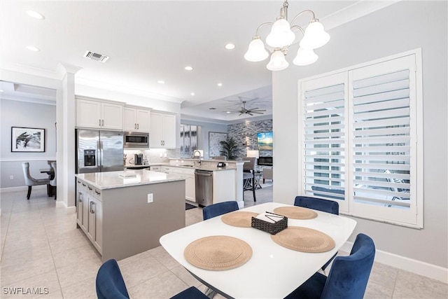 dining space with crown molding, sink, ceiling fan with notable chandelier, and light tile patterned floors