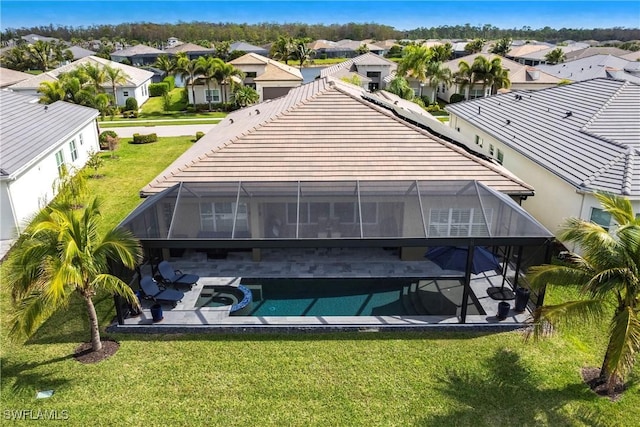 back of property featuring a lanai, a yard, a patio area, and a pool with hot tub