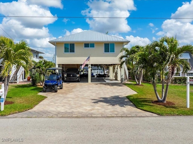 coastal inspired home with a carport and a front lawn