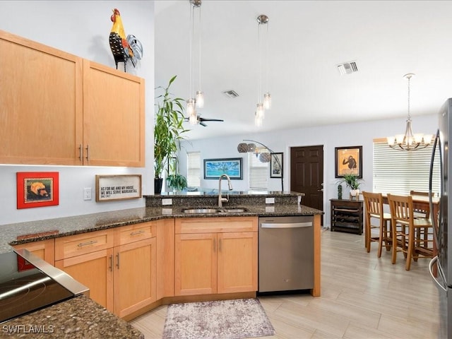 kitchen with stainless steel appliances, decorative light fixtures, light brown cabinetry, and sink