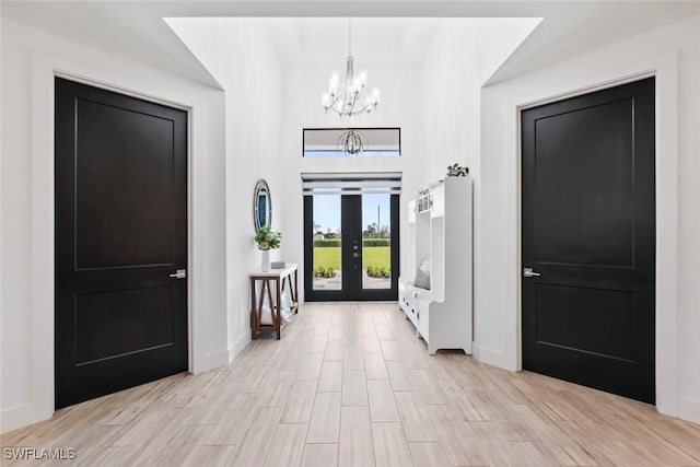 entrance foyer with an inviting chandelier, light hardwood / wood-style floors, and french doors