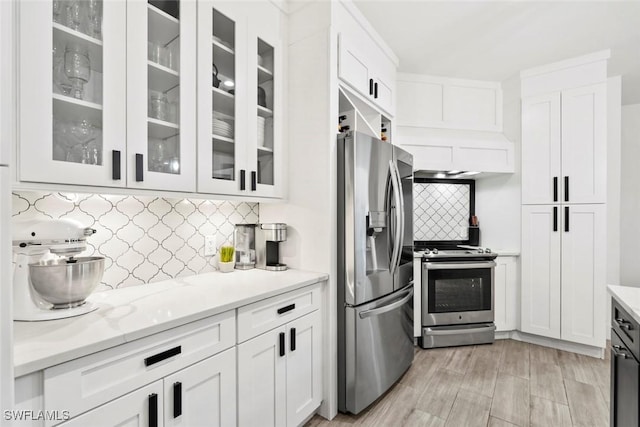 kitchen with white cabinetry, decorative backsplash, stainless steel appliances, and light stone counters