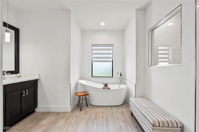 bathroom with hardwood / wood-style flooring, a tub to relax in, and vanity