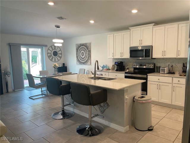 kitchen featuring appliances with stainless steel finishes, sink, white cabinetry, and a center island with sink