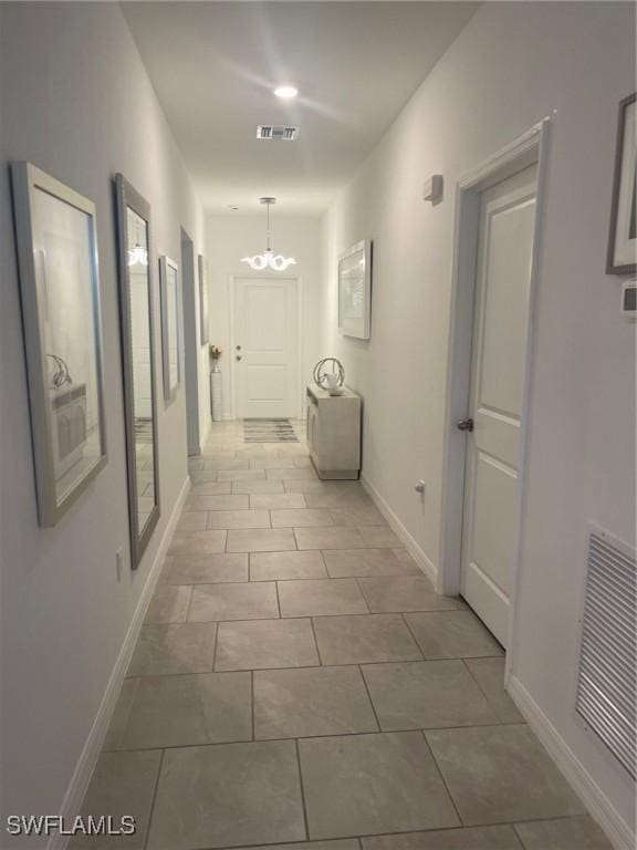 hallway featuring light tile patterned floors and a chandelier