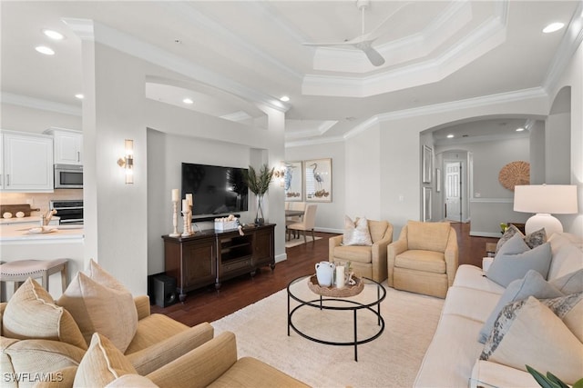 living room with ceiling fan, ornamental molding, dark hardwood / wood-style floors, and a raised ceiling