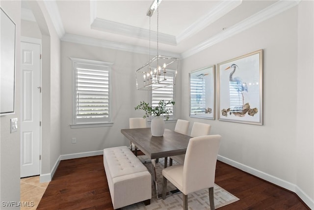 dining space featuring crown molding, wood-type flooring, a raised ceiling, and a chandelier