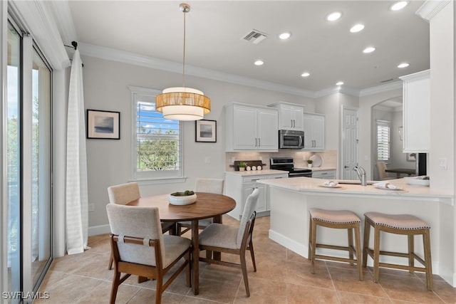 dining room with crown molding, sink, and light tile patterned floors