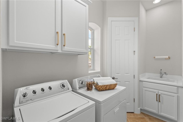 washroom with cabinets, sink, light tile patterned floors, and washer and clothes dryer