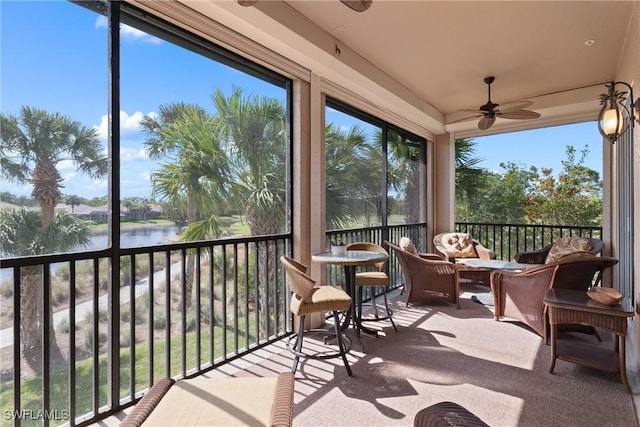 sunroom / solarium with ceiling fan and a water view