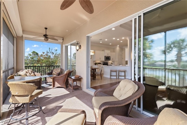 sunroom / solarium with a water view and ceiling fan