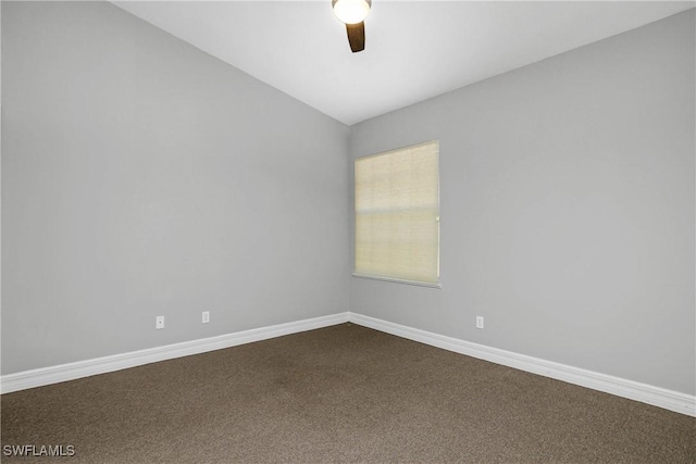 unfurnished room with vaulted ceiling, dark colored carpet, a ceiling fan, and baseboards