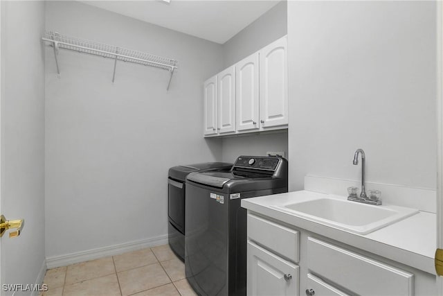 laundry area with light tile patterned flooring, a sink, baseboards, washer and dryer, and cabinet space