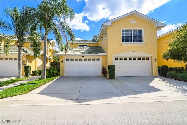 traditional home with driveway, a tiled roof, and stucco siding