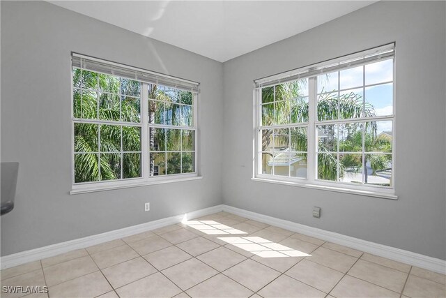 empty room with light tile patterned floors and baseboards