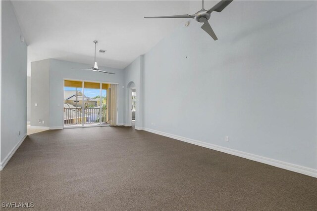 unfurnished living room with arched walkways, visible vents, dark carpet, ceiling fan, and baseboards