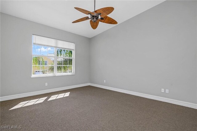 unfurnished room with vaulted ceiling, dark colored carpet, a ceiling fan, and baseboards