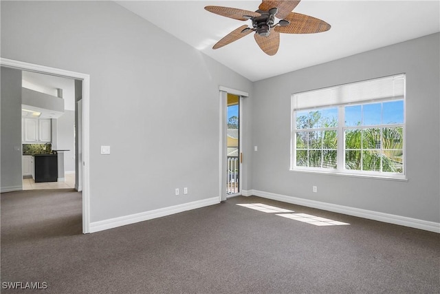 carpeted spare room featuring lofted ceiling, baseboards, and a ceiling fan