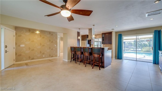 kitchen featuring light countertops, baseboards, a kitchen bar, visible vents, and wallpapered walls