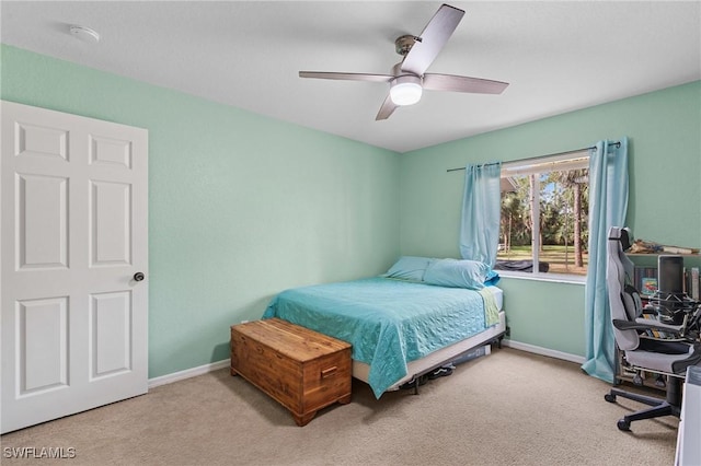 bedroom featuring light carpet, a ceiling fan, and baseboards