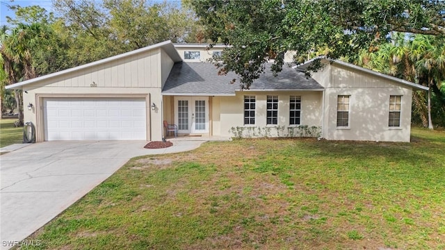 view of front of house featuring a garage, driveway, roof with shingles, french doors, and a front yard