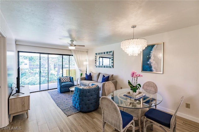 dining area with wood-type flooring and ceiling fan with notable chandelier