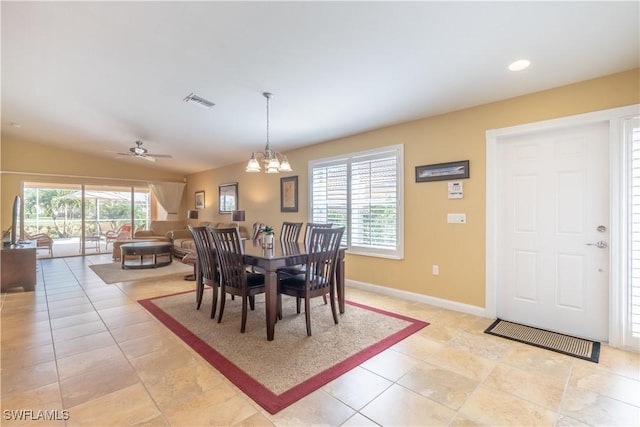 tiled dining space featuring lofted ceiling, ceiling fan with notable chandelier, and a healthy amount of sunlight