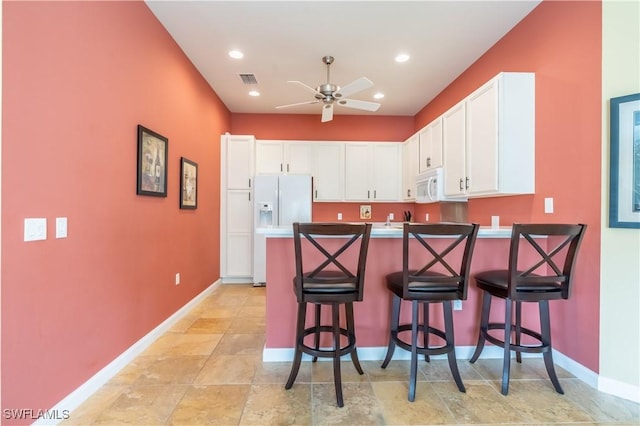 kitchen featuring a breakfast bar, white cabinets, ceiling fan, kitchen peninsula, and white appliances