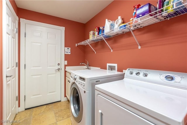 clothes washing area featuring cabinets, washer and clothes dryer, and sink